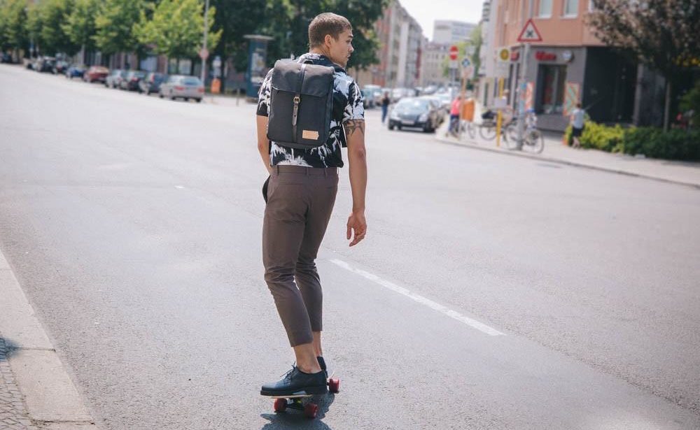 Mann auf einem Skateboard mit Rucksack